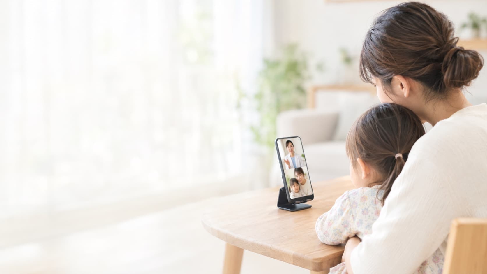 スマホで小児科医の診察を受ける保護者とお子さん